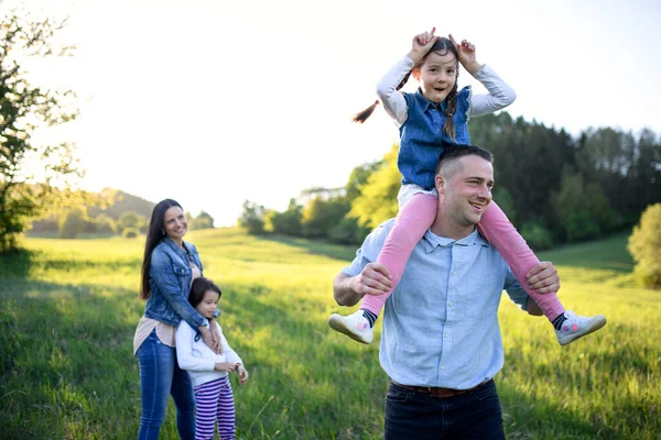 Gelukkige familie met twee kleine dochters hebben plezier buiten in de lente natuur. — Stockfoto