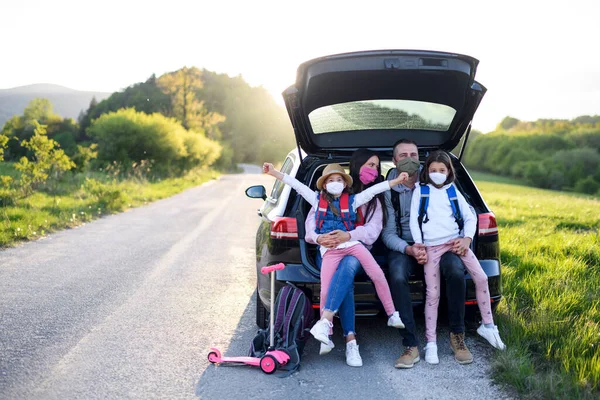 Famiglia con due piccole figlie in viaggio all'aria aperta nella natura, indossando maschere per il viso . — Foto Stock