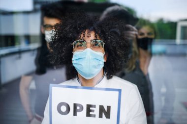 Yüz maskeli bir adamın portresi açık tabela, karantina ve kilit kavramı içeriyor..