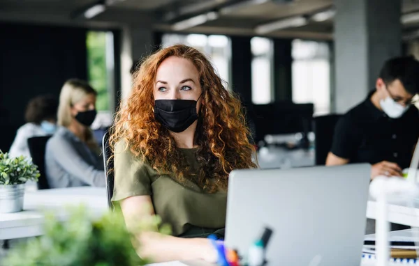 Jovem com máscara facial de volta ao trabalho no escritório após o bloqueio. — Fotografia de Stock