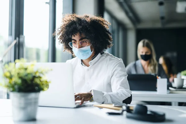 Portrait of young man with face mask back at work in office after lockdown. — Stock Photo, Image