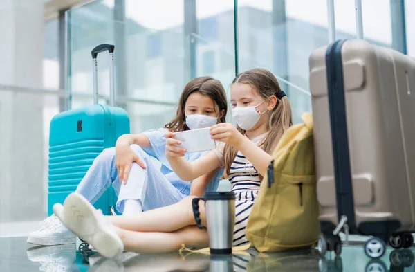 Маленькі діти зі смартфоном, що йдуть у відпустку, носять маски для обличчя в аеропорту . — стокове фото