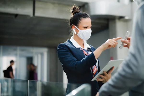 Flight attendant talking to businessman on airport, wearing face mask. — Stock Photo, Image