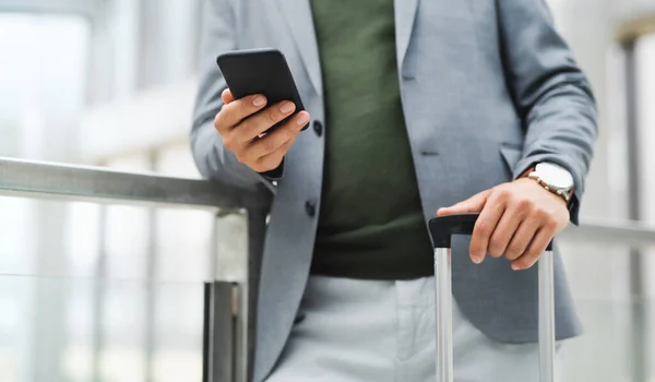 Onherkenbare zakenman met bagage op zakenreis, met smartphone. — Stockfoto