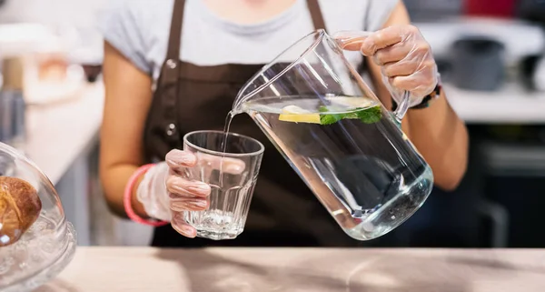 Donna irriconoscibile con guanti che lavorano nel caffè, versando acqua. — Foto Stock