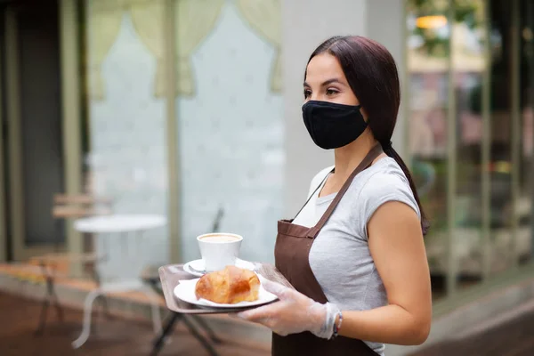 Young woman with face mask working in cafe, serving customers. — Stock Photo, Image