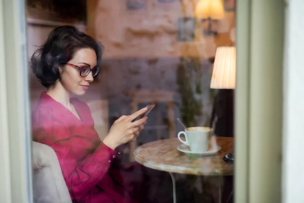 Jovem com café sentado em casa no café, usando smartphone . — Fotografia de Stock
