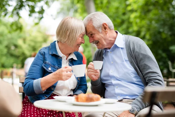 Счастливая влюбленная старшая пара, сидящая на открытом воздухе в кафе, веселясь. — стоковое фото