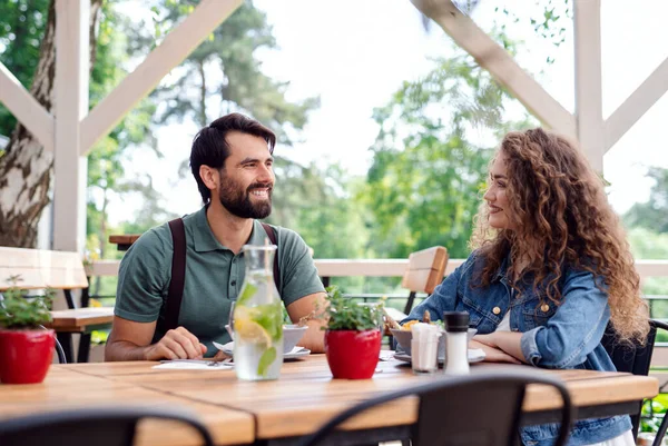 Šťastný pár sedí venku na terase restaurace, mluví. — Stock fotografie