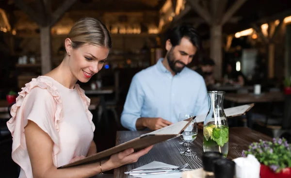 Happy couple sitting indoors in restaurant, looking at menu. — Stock Photo, Image