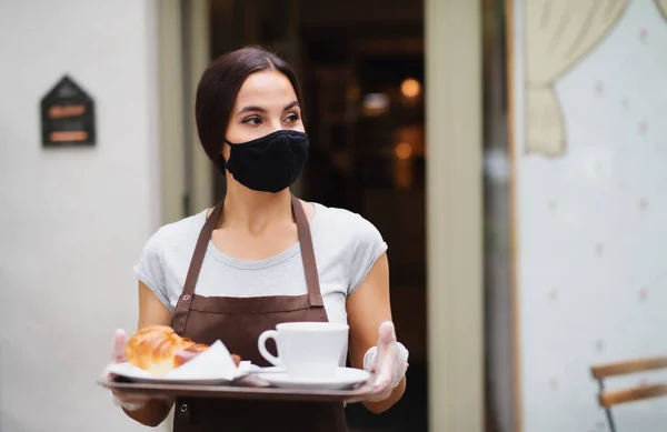 Официантка в маске работает в кафе, обслуживает клиентов . — стоковое фото
