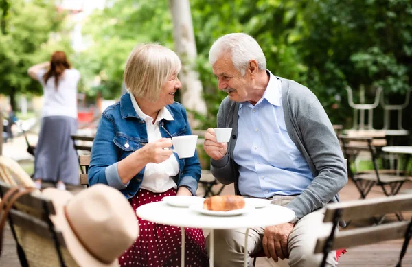 Šťastný zamilovaný starší pár sedí venku v kavárně a povídá si. — Stock fotografie