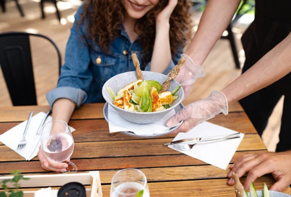 Garçons irreconhecíveis com luvas que servem os clientes ao ar livre no restaurante terraço . — Fotografia de Stock