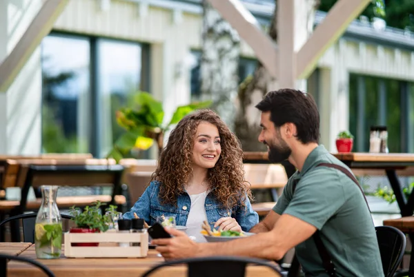 Szczęśliwa para siedzi na zewnątrz na tarasie restauracja, rozmowy. — Zdjęcie stockowe