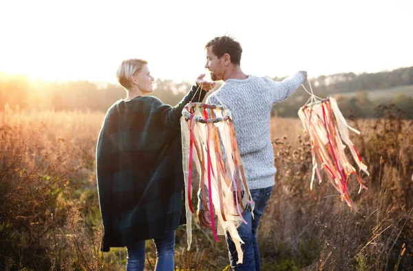 Joven pareja enamorada en un paseo en el bosque de otoño, sosteniendo cometas de cinta de mano. — Foto de Stock