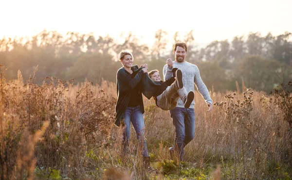 秋の自然を歩く小さな息子を持つ美しい若い家族. — ストック写真