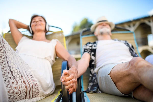 Seniorenpaar mit Kopfhörern im Urlaub im Freien, entspannend. — Stockfoto