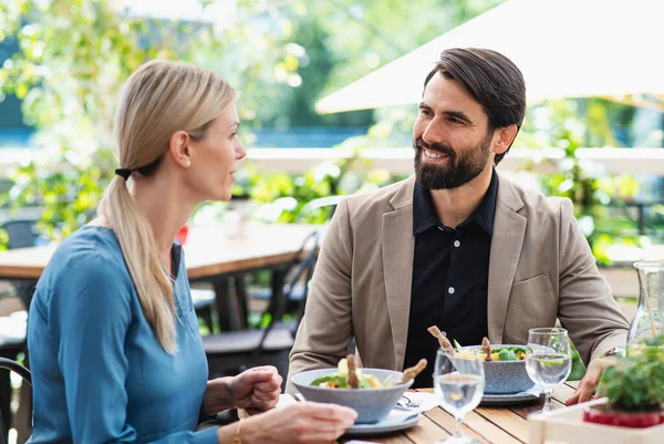 Szczęśliwa para siedzi na zewnątrz na tarasie restauracja, rozmowy. — Zdjęcie stockowe