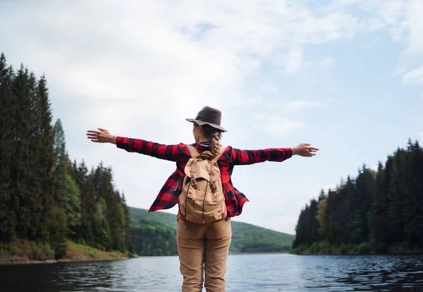 Vue arrière de la jeune femme au bord du lac lors d'une promenade en plein air dans la nature estivale, relaxant. — Photo