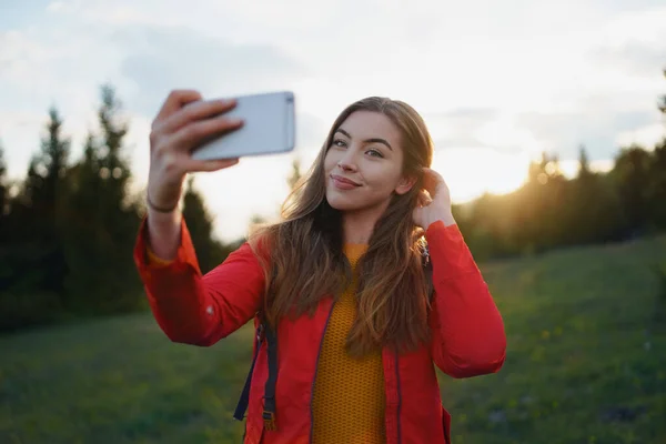 Mladá žena na procházce venku na louce v letní přírodě, přičemž selfie. — Stock fotografie