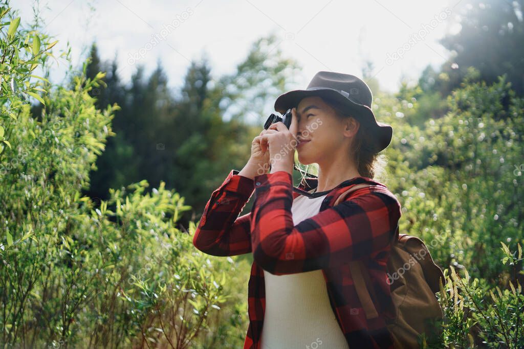 Young woman with a dog on a walk outdoors in summer nature, taking photographs.