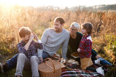 Sonbahar doğasında küçük çocuklu güzel bir aile piknik yapıyor..