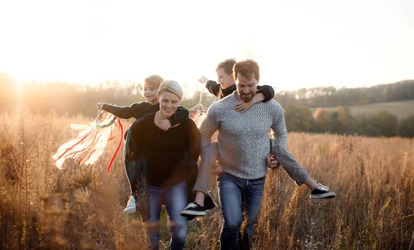 Bela família jovem com crianças pequenas em um passeio na natureza de outono . — Fotografia de Stock
