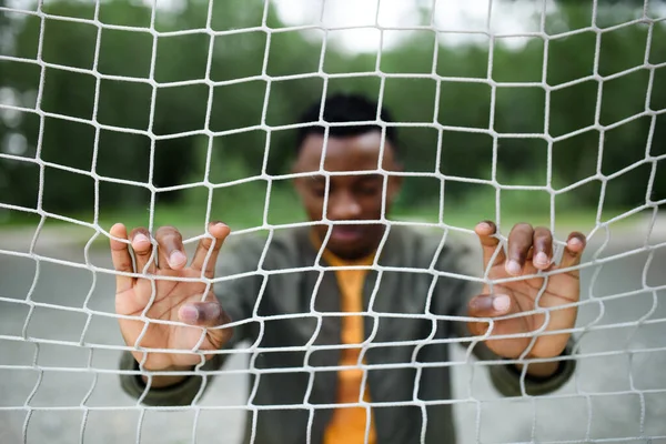 Frusztrált fiatal fekete férfi háló mögött szabadban a városban, fekete élet anyag koncepció. — Stock Fotó