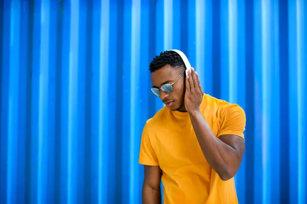 Jovem homem negro com fones de ouvido em pé contra fundo azul, preto vidas matéria conceito . — Fotografia de Stock