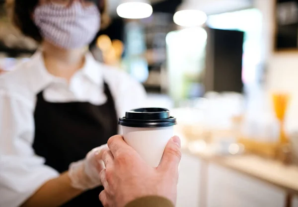 Αγνώριστη σερβιτόρα με μάσκα προσώπου που εργάζεται σε καφετέρια, εξυπηρετώντας πελάτες. — Φωτογραφία Αρχείου