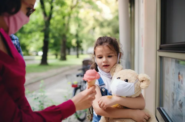 Madre irreconocible con máscara facial comprando helado para hija pequeña en la ciudad . —  Fotos de Stock