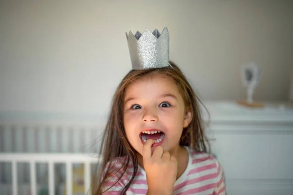Retrato de niña pequeña con corona de princesa en la cabeza en el interior, mirando a la cámara . — Foto de Stock