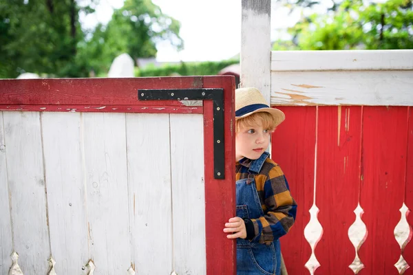 Small boy on farm, opening red and white gate. — Stock Photo, Image