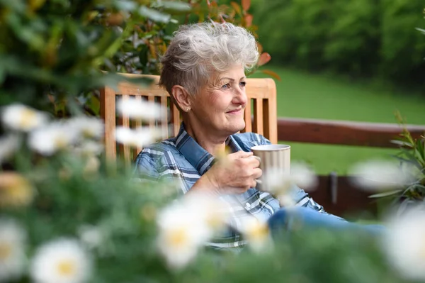 Mujer mayor con café sentado en la terraza en verano, descansando. —  Fotos de Stock