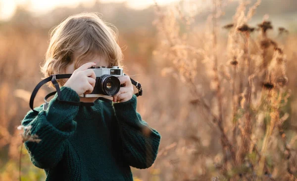 Menina pequena na natureza outono, tirando fotografias com câmera. — Fotografia de Stock