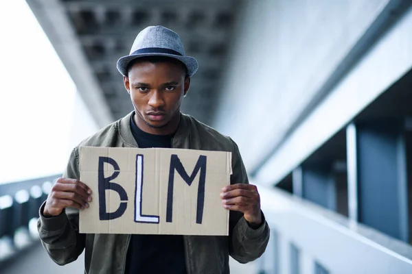 Людина з BLM знаком стоячи на відкритому повітрі, чорне життя має значення концепції. — стокове фото