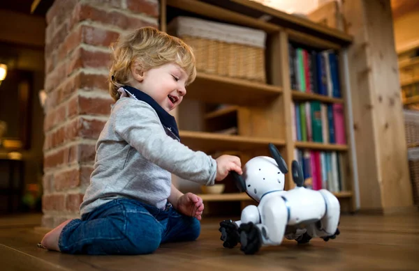 Милый малыш, стоящий дома, играющий с роботизированной собакой. — стоковое фото