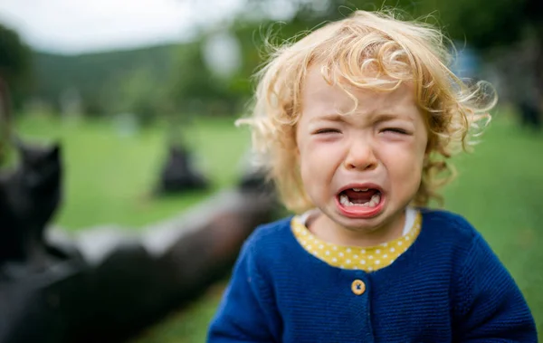 Portrait of small girl outdoors in garden, crying. — Stock Photo, Image