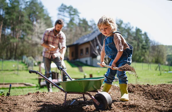 Padre con hijo pequeño que trabaja al aire libre en el jardín, concepto de estilo de vida sostenible. —  Fotos de Stock