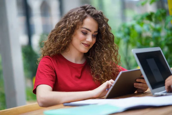 Mujer joven con la tableta sentada en el interior de la oficina, trabajando. — Foto de Stock