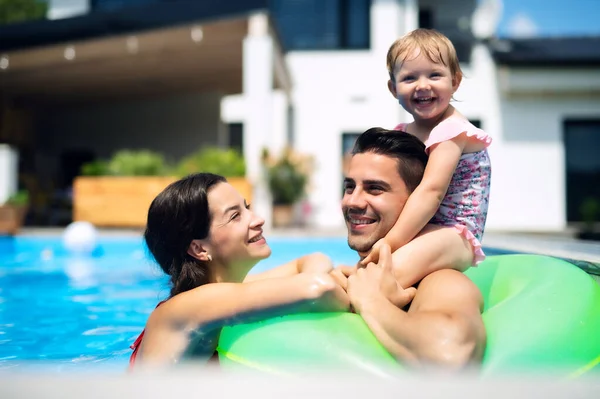 Familia joven con hija pequeña en la piscina al aire libre en el jardín del patio trasero. —  Fotos de Stock