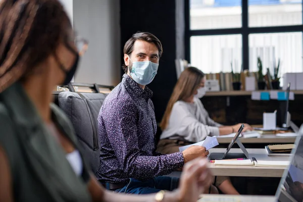 Portret van jonge ondernemers met gezichtsmaskers die binnen in het kantoor werken. — Stockfoto