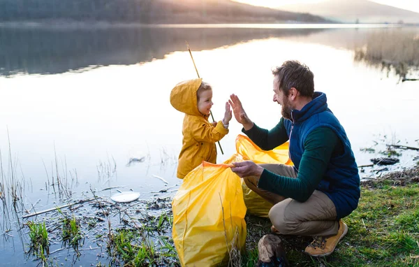 Padre con hija pequeña recogiendo basura al aire libre en la naturaleza, el concepto de trote. —  Fotos de Stock