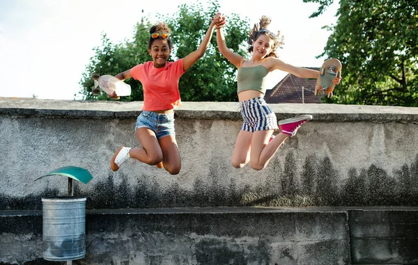 若いですティーン女の子友人とともにスケートボード屋外で市,ジャンプ. — ストック写真