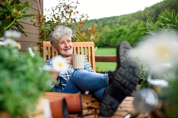 Senior kvinna med kaffe sittande på terrassen på sommaren, vila. — Stockfoto