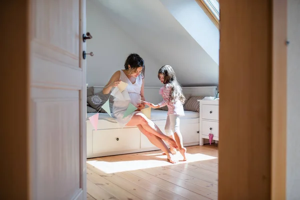 Retrato de mulher grávida com pequena filha dentro de casa, brincando. — Fotografia de Stock