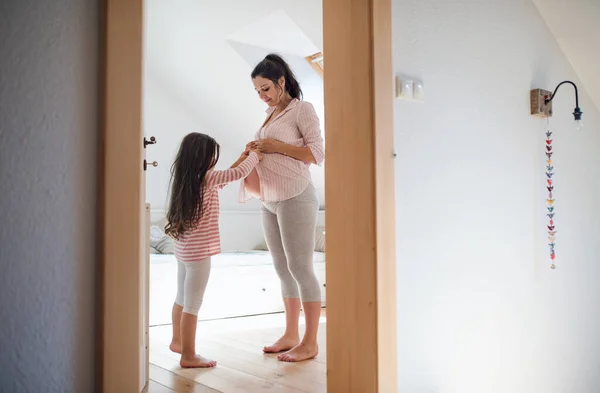 Portrait of pregnant woman with small daughter indoors in bathroom at home. — Stock Photo, Image