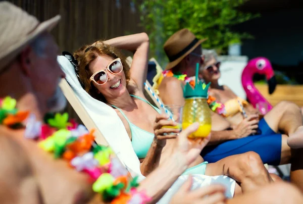 Groupe d'aînés joyeux assis près de la piscine à l'extérieur dans la cour, concept de fête. — Photo