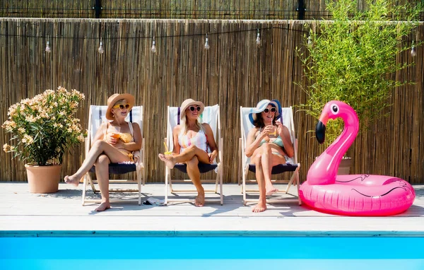 Skupina veselých žen senioři sedí u bazénu venku na dvorku. — Stock fotografie