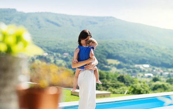 Jonge moeder houden kleine dochter buiten in achtertuin. — Stockfoto